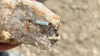 Person's hand holding a rock with beryl crystal.